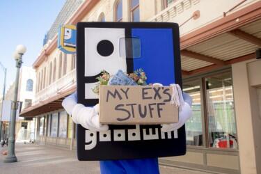 Goodwilliam Mascot holding a box of donated items labeled "My Ex's Stuff"